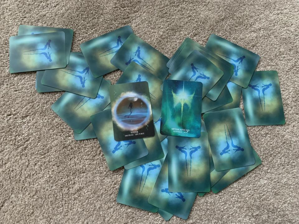 A spread of oracle cards on the floor, suggesting reflection, insight, and exploring kindness as an inner home